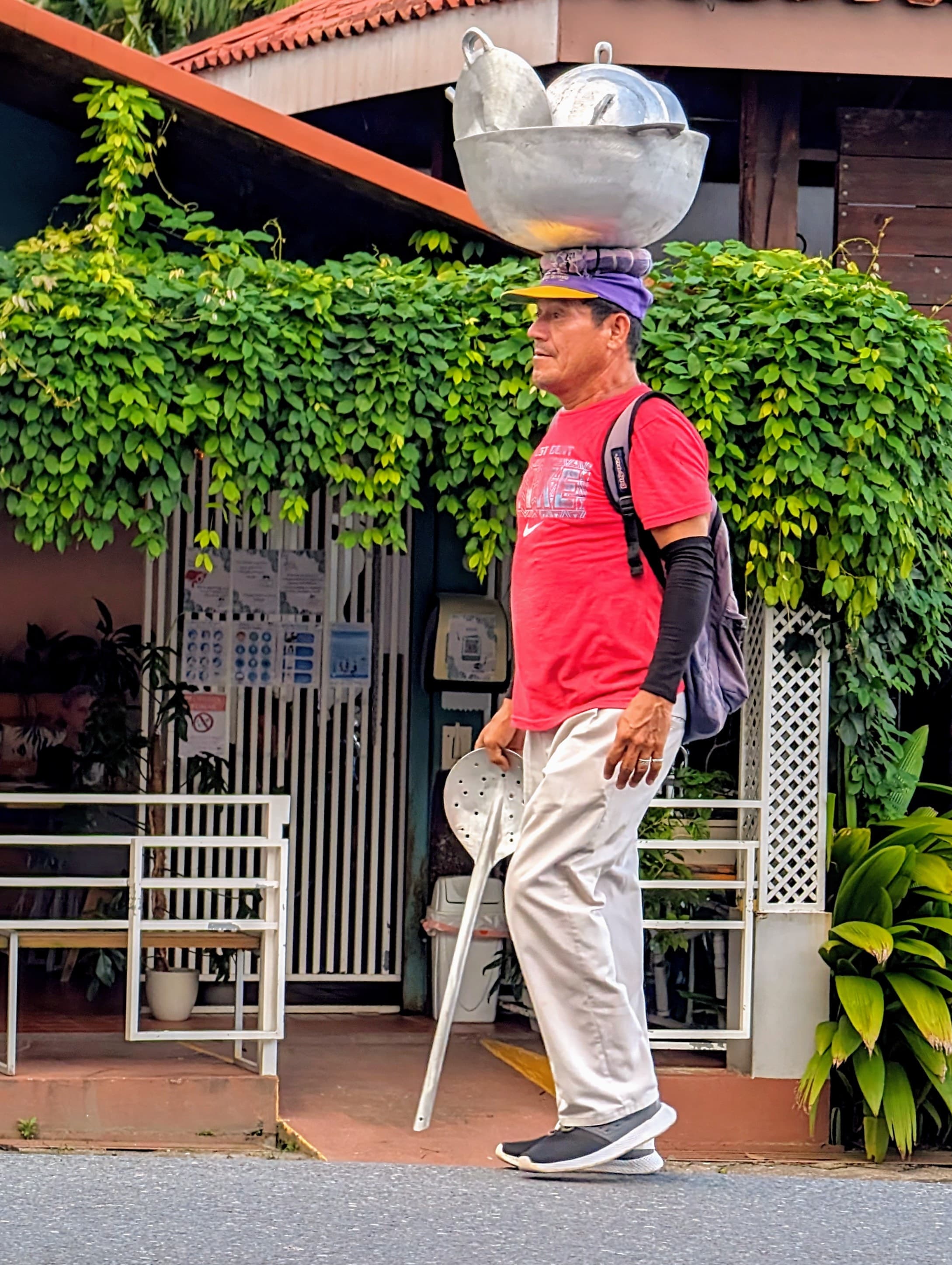Walking through La Fortuna with pots balanced on his head, looking as though he is on his way to work.