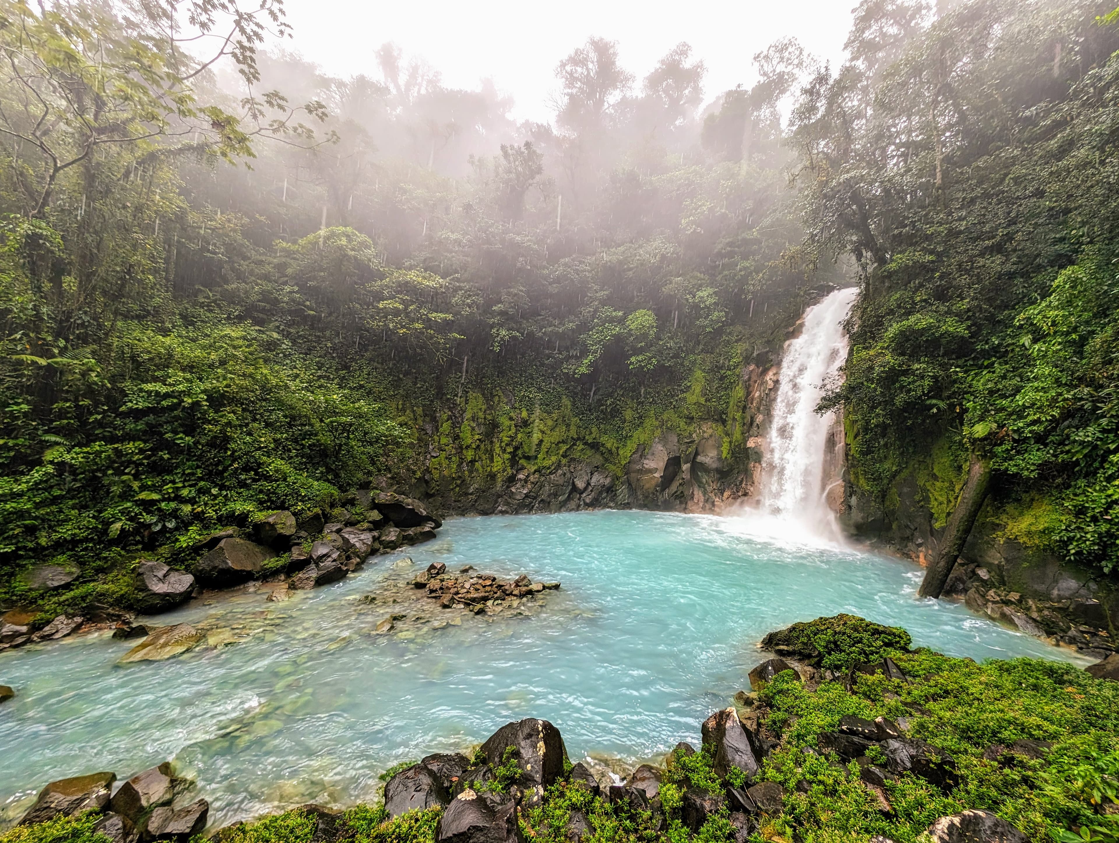 At Río Celeste, mixing streams lowers the pH, causing tiny aluminosilicate particles to clump together and scatter sunlight, giving the waterfall its vivid blue water.