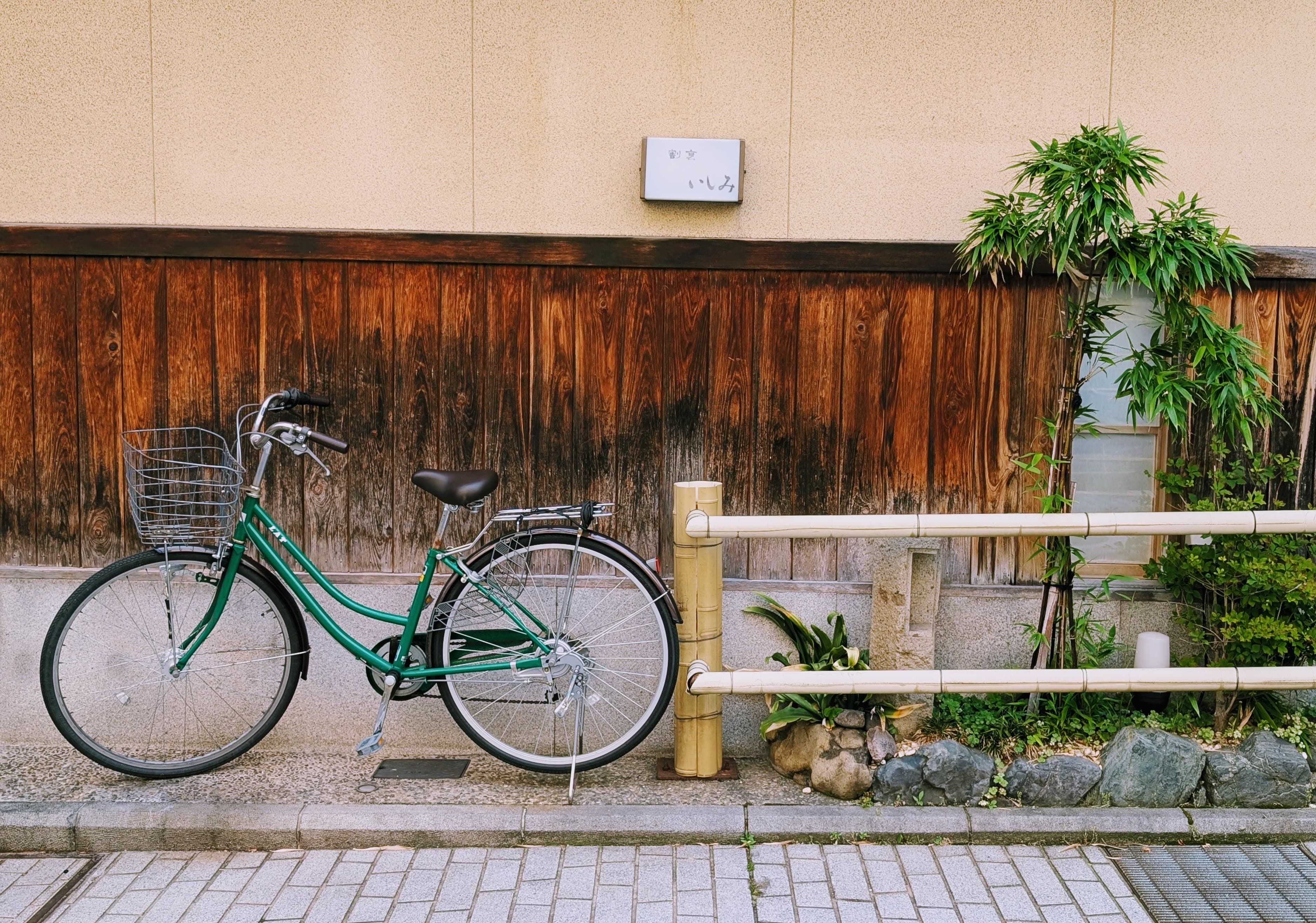 A green bicycle against a wooden wall in Kanazawa.