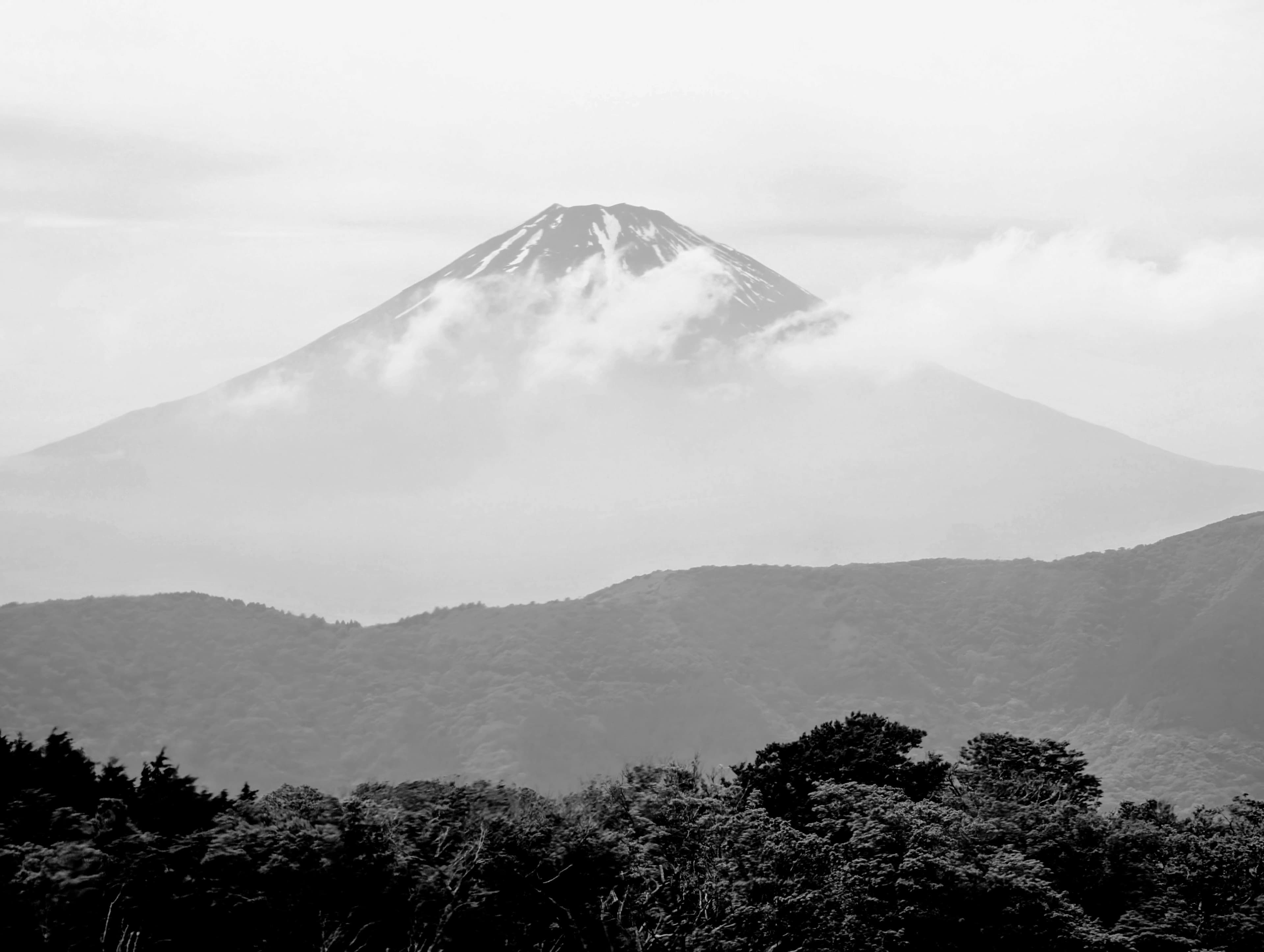 Snow-streaked Mount Fuji rises above the clouds.